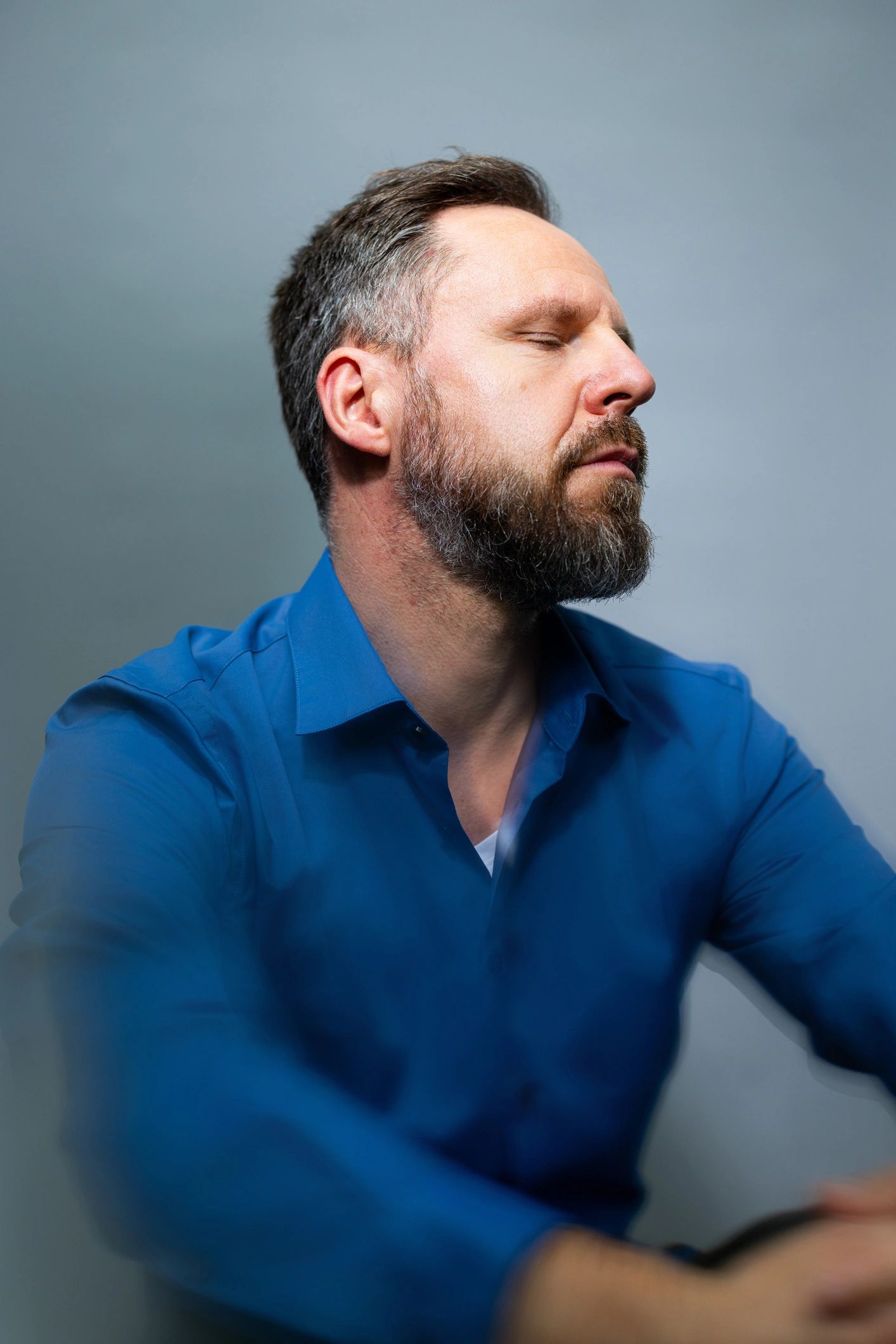 Reflective mature man with eyes closed against a neutral background